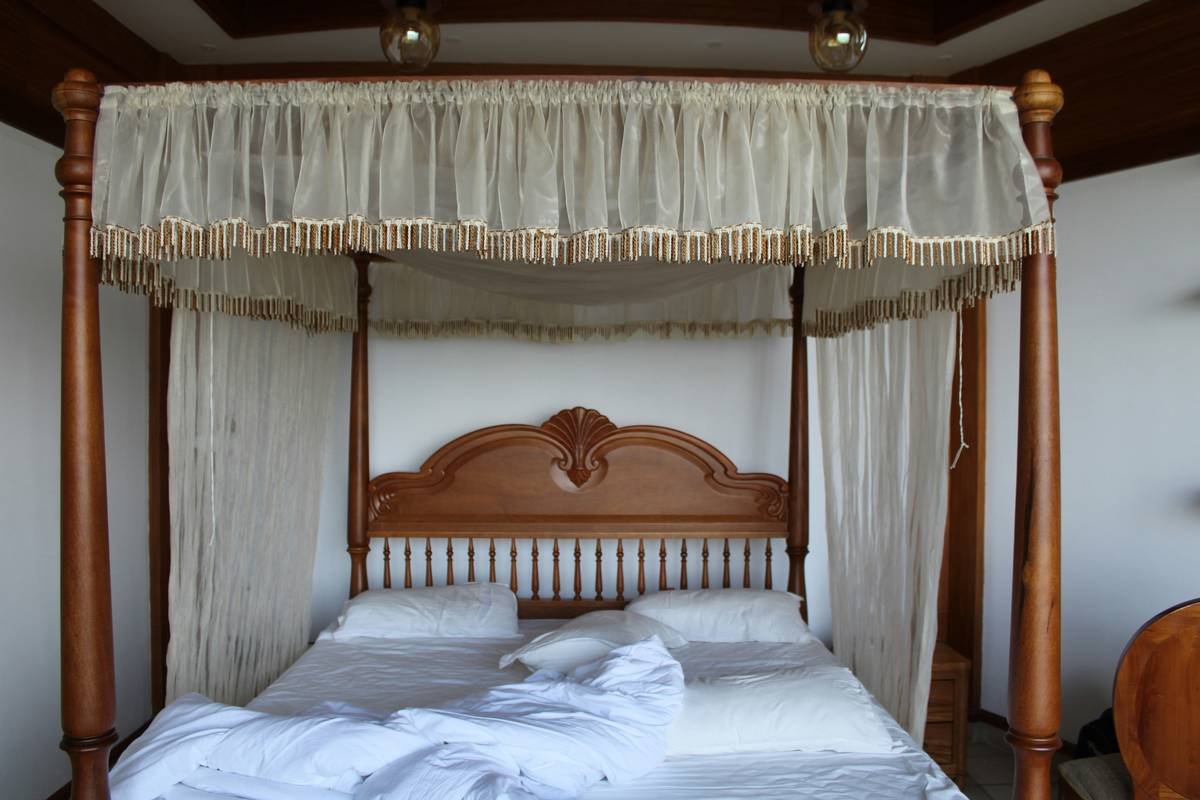 Side-by-side comparison: traditional ornate canopy bed vs. clean-lined modern canopy wood bed in walnut finish