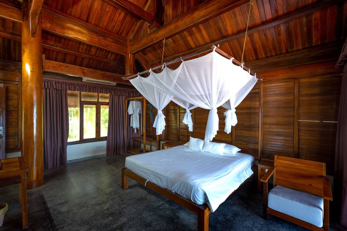 Comparison chart showing indoor vs. outdoor canopy bed materials: teak vs. pine, Sunbrella vs. cotton, powder-coated steel vs. untreated iron